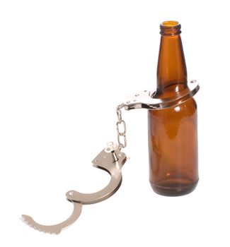 Concept image of drinking illegally featuring a beer bottle and a pair of handcuffs, isolated against a white background