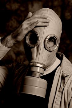 A dark image featuring someone wearing a gas mask holding his head