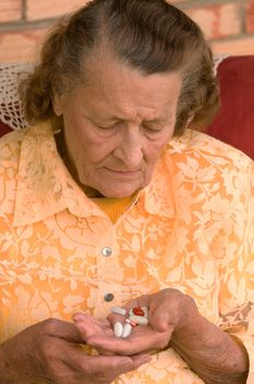 senior looking down at a handful of pills