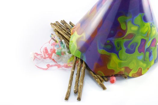 Salty brown tasty pretzels with cone shaped party hat and streamers on a reflective white background