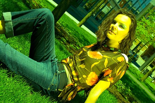 Teenage girl sitting in a park on the grass under the noon sun