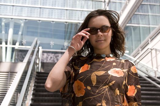 Young women coming downstair of a building with a great smile, adjusting her sunglasses