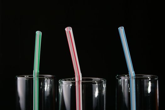 Glass with straw for cocktails on a black background.