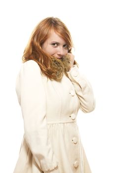 young redhead woman covering her face in fawn winter coat on white background