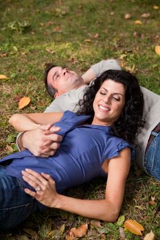 A man and woman relaxing in the park laying in the grass and dreaming - focus on the woman