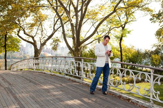 A man checking his cell phone in a park