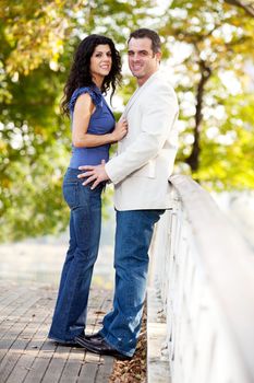 A happy couple in a park on a bridge looking at the camera