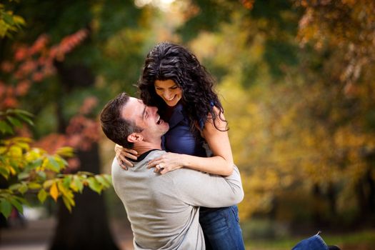 An excited couple giving eachother a big hug in a park