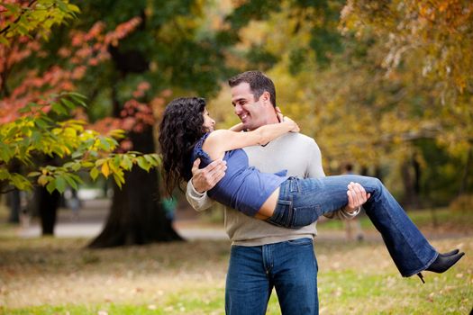 A man holding a woman in a park - happy couple