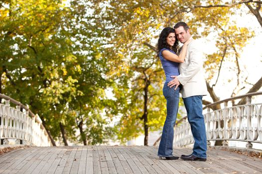 A happy couple in the park looking at the camera and hugging