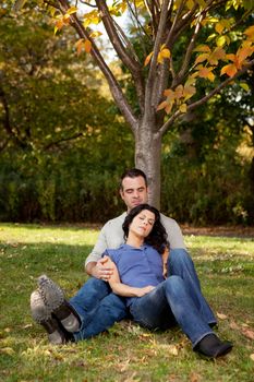 A couple relaxing in the park by a tree