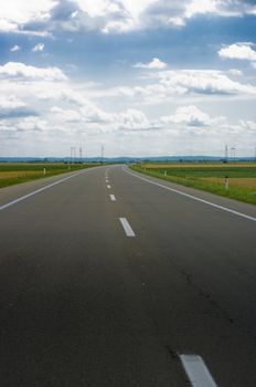 A long road with right direction with scenic clouds in a blue sky