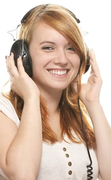 laughing redhead girl with headphones listening to music on white background