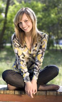 A young blond girl relaxing outdooers in a park in a warm sunny day