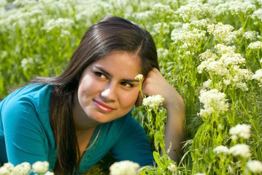 young asian woman relaxing and enjoying the sun on a meadow with flowers