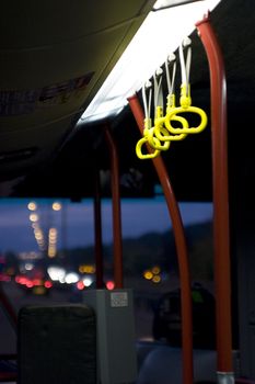 Bus interior showing handles and the road ahead from the perspective of a traveller