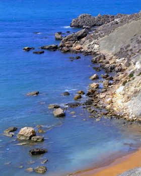 Clear blue Mediterranean waters on windy day, with beach and typical rocky coastline