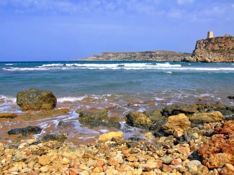 Clear blue Mediterranean waters on windy day, with beach and typical rocky coastline