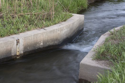 irrigation ditch with a flow measurement concrete structure and water scale, Colorado
