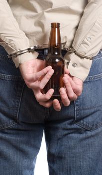 A concept image of a man arrested for drinking a driving featuring a man holding a beer bottle with his hands cuffed behind his back