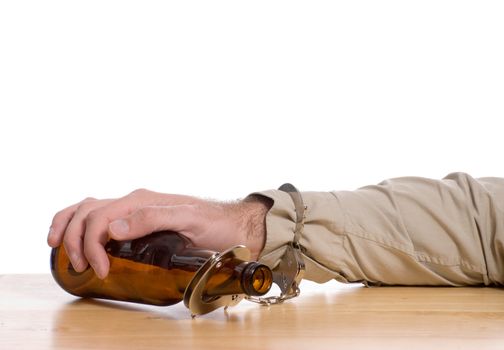 A mans hand is handcuffed to a bottle of beer,  with white copyspace above