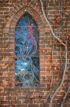 excellent image of a stained glass church window with last spray of autumn red leaves
