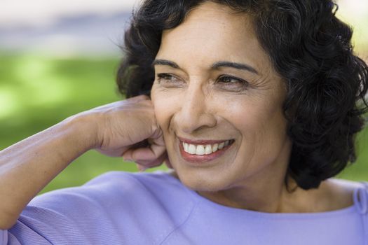 Portrait of a Smiling Indian Woman Sitting on a Bench in Park