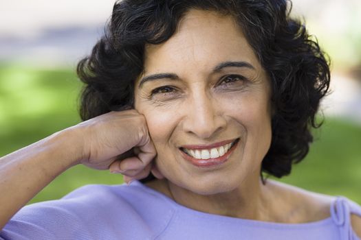 Portrait of a Smiling Indian Woman Sitting on a Bench in Park