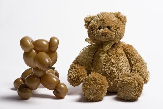 Brown balloon bear and teddy bear sitting side by side