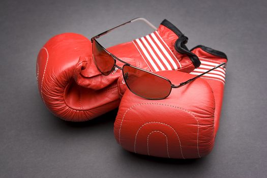 Men's sunglasses place on top of boxing gloves 