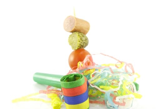 Cocktail stick with sausage, gherkin and tomato with streamer and blower on a white background