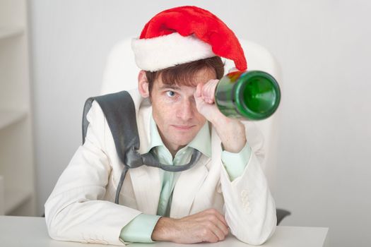 The amusing guy in a Christmas cap with a bottle in a hand