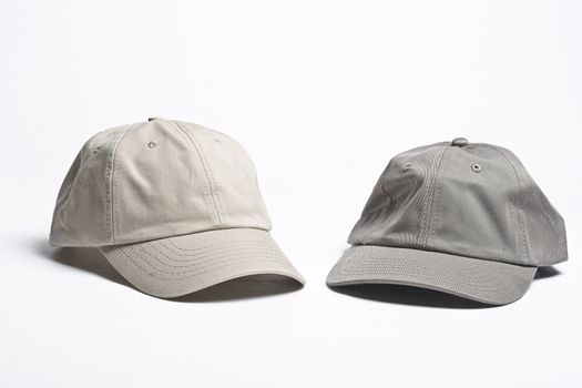 two plain beige baseball caps of different tint