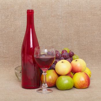 Still-life from a red bottle of wine and fruit against a canvas