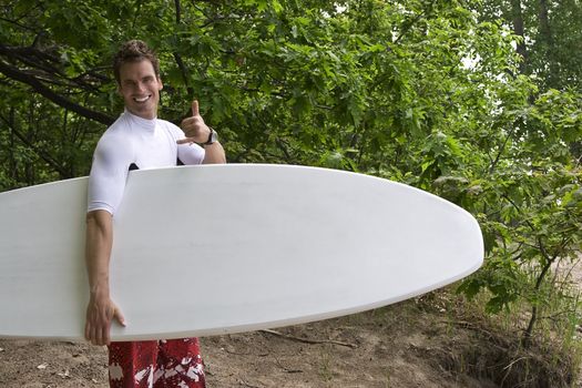 Male surfer in the wood saluting with a shaka gesture