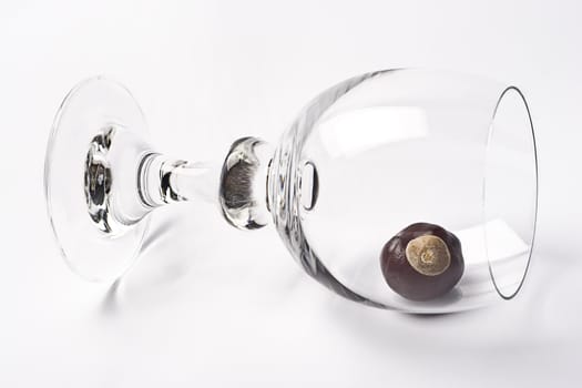 Glass of wine tipped over containing one chestnut