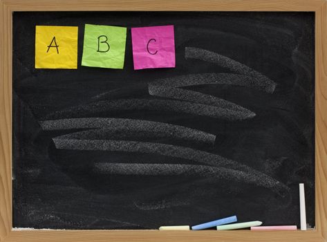 A, B, C - first three letters of alphabet displayed with sticky notes on blackboard with white chalk smudge pattern