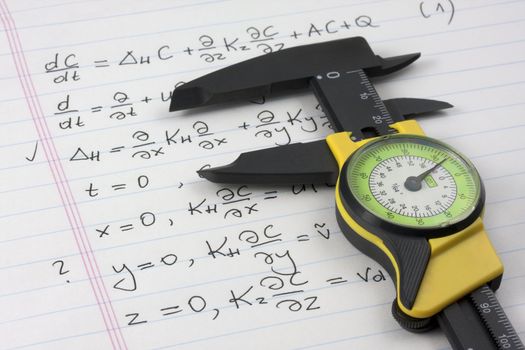 mathematics or physics learning concept - caliper seizing mathematical equations handritten on notebook page