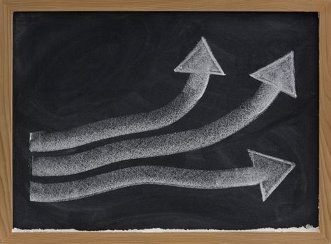 growth, progress or success concept presented with thick white chalk arrows on blackboard, eraser smudges