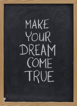 make your dream come true - motivational slogan handwritten with white chalk on blackboard