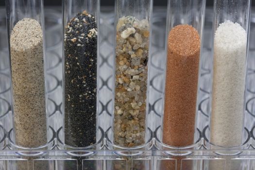 five glass testing tubes with different sand samples collected from beaches and deserts of western USA and Hawaii