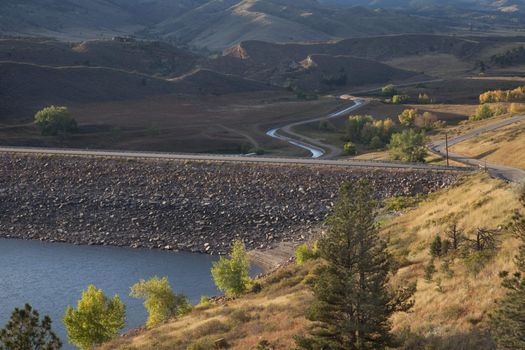 rock dam on Horsetooth Reservoir at foothills of Rocky Mountains near Fort Collins, Colorado, Charles Canal below the dam is running water, early fall