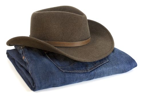 felt wool brown (olive) cowboy hat and blue folded jeans on white background