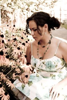 Twenty something columbian women smelling daisies in a garden