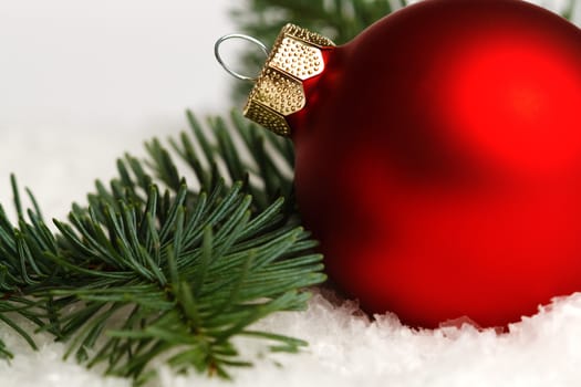 A red christmas balls, fir branch on snow, isolated on white background