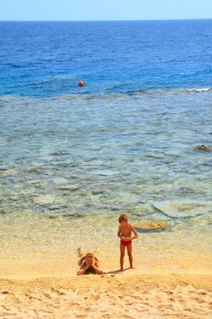 ma and son playing on beach on background blue sky