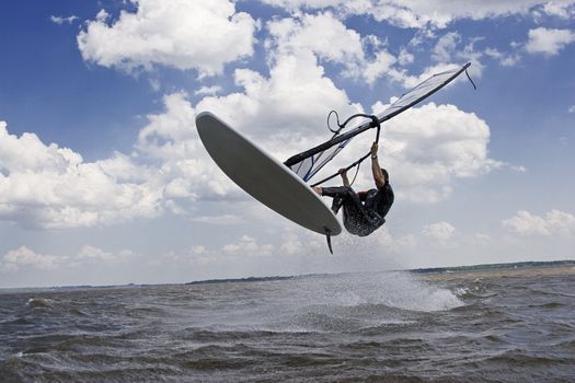 Windsurfer doing a jump trick in the water and catching lots of air