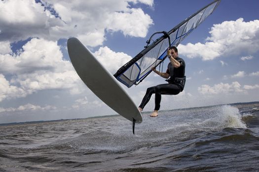 Windsurfer doing a jump trick in the water and catching lots of air