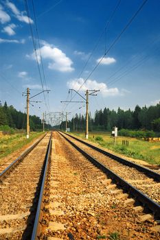 Old Steel Railroad Tracks with reflection under bkue sky anf clouds