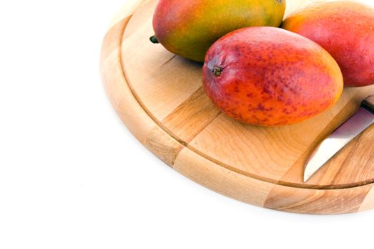Ripe juicy mangoes on a wooden cutting board on a white background